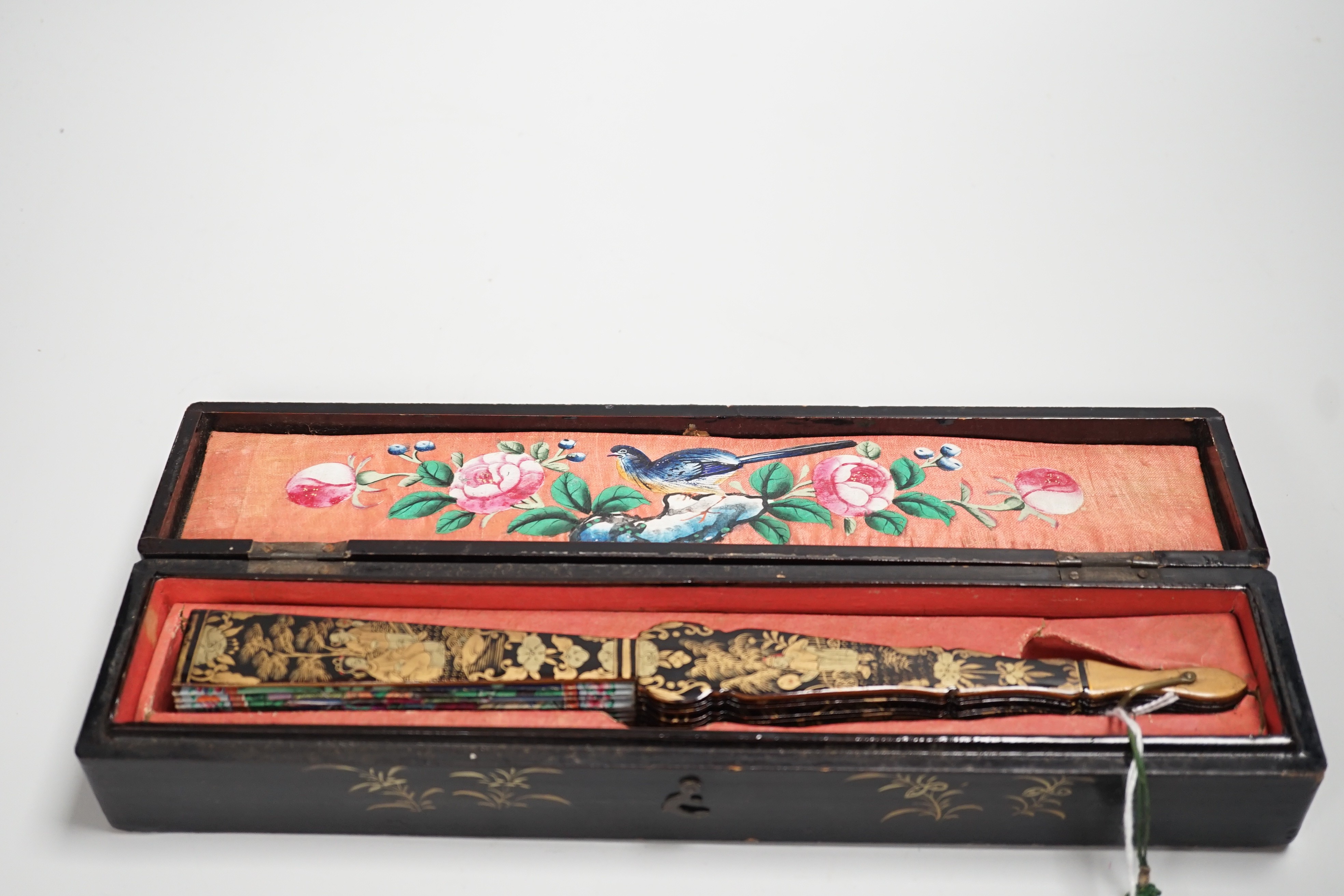 A 19th century Chinese painted paper leaf and lacquer painted fan in a gilt decorated black lacquer fitted case, the fan with painted ivory appliqué faces, 28cm